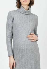 Graues, geripptes Rollkragenkleid mit langen Ärmeln, aus weichem Stoff gefertigt. Es hat eine figurbetonte Silhouette mit vertikalem Muster und einem gemütlichen Kragen.