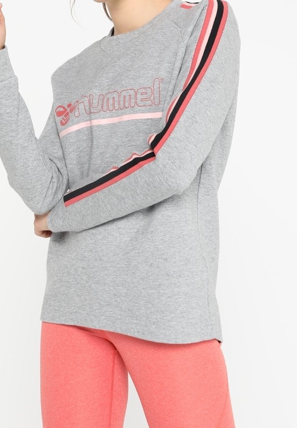 Sudadera gris con rayas rosas y negras en las mangas, con el logo "hummel" en el pecho. Combinada con leggings rosas.