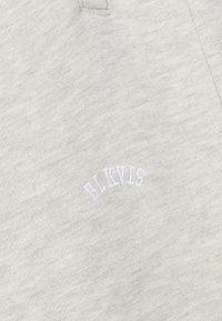 Helle graue Sweatshirtwäsche mit einer weichen Textur, versehen mit einem weißen gestickten "BLKVLS"-Logo in einem gewölbten Design am unteren Vorderteil.