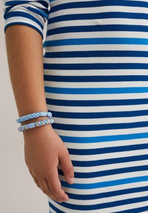 Blå och vit randig ribbad klänning, med accentfärger i olika nyanser av blått. Handleden pryds av tre mönstrade och enfärgade armband.