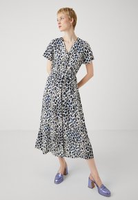 Abito leggero e a maniche corte con design a portafoglio in stampa animalier bianca, blu e nera. Presenta una cintura con fiocco e gonna svasata.