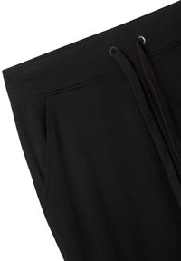 Pantaloni della tuta neri con vita elastica, cordini regolabili, tasche laterali e materiale in cotone liscio. Design minimale senza motivi.