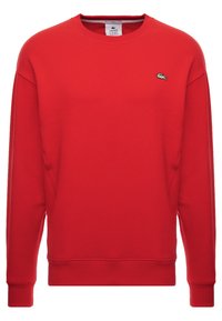 Felpa rossa a maniche lunghe con collo a girocorte e piccolo logo coccodrillo bianco e verde di Lacoste sul lato sinistro del petto.
