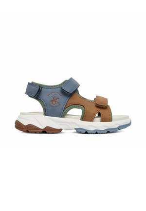Børnesportsandal med blå og brune remme, justerbare lukninger og en hvid tekstureret sål til udendørs aktiviteter.
