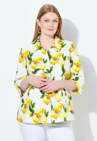 Camicia bianca a maniche lunghe con un vivace motivo di limoni accompagnato da foglie verdi e dettagli gialli. Maniche a tre quarti e un design di vestibilità morbida.