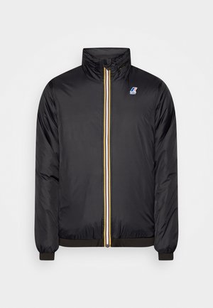 Veste noire zippée avec col montant, détail de la fermeture éclair rayé en jaune, blanc et noir, et petit logo K-Way sur la poitrine.