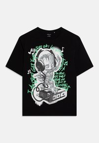 T-shirt en coton noir avec un imprimé graphique d'un personnage portant des écouteurs, avec du texte vert et des notes de musique sur un fond contrastant.