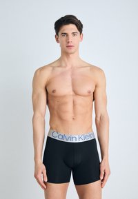 Fekete pamut boxer alsónadrág szürke derékrésszel, kék "Calvin Klein" logóval. Simíts textúra és testhez simuló kialakítás.