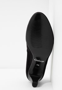 Semelle d'une chaussure pour femme en daim noir, taille 4½, avec une texture antidérapante et un talon bas, étiquetée "Gabor" et "Fabriqué au Portugal".