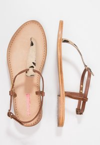 Hnědé kožené sandály s akcenty zvířecího vzoru, plochou podrážkou a nastavovacími popruhy. Hladký povrch a minimalistický design.