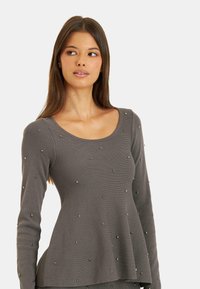 Szary, prążkowany, długi top z falbaniastym dołem i ozdobami w postaci małych metalowych ćwieków na całej powierzchni materiału.