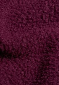 Tessuto borgogna con superficie morbida e pelosa. Il materiale appare caldo e denso, con un motivo leggermente irregolare.