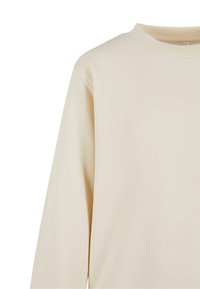 Ljus beige sweatshirt med ribbad rund hals, långa ärmar och ett mjukt, texturerat tyg. Har en avslappnad passform och en minimalistisk design.