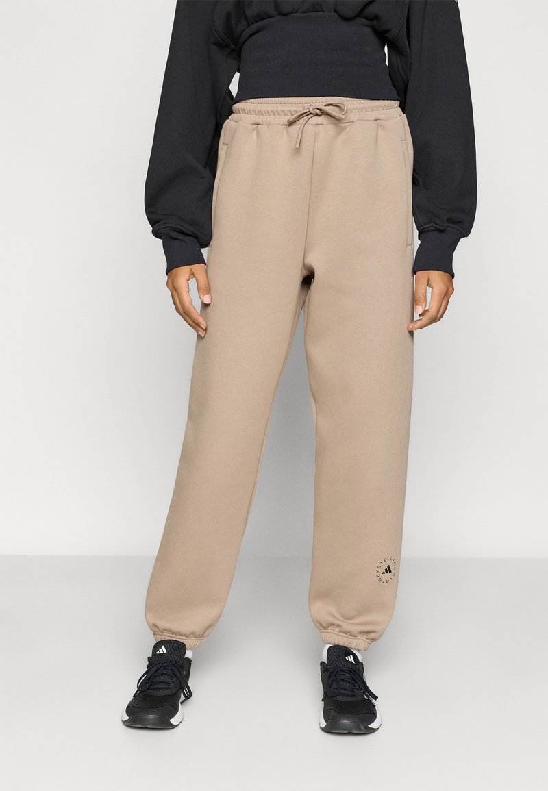 Μπεζ φόρμα με ελαστική μέση και κορδόνι, με πλαϊνές τσέπες και κυκλικό λογότυπο κοντά στο τελείωμα.