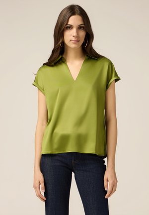 Blusa in raso verde con scollatura a V, maniche corte e una vestibilità ampia. Il design include una texture liscia con una leggera lucentezza.