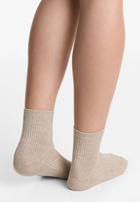 Calze rigate beige con altezza fino al polpaccio, caratterizzate da una morbida texture e un design strutturato, con cuciture dettagliate sul tallone e sulla punta.