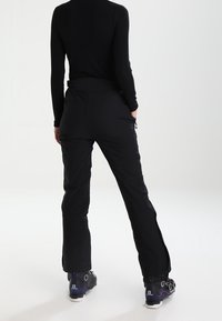 Pantalones aislantes negros con diseño de pierna recta, con cremalleras laterales en los tobillos y cintura elástica para mayor comodidad.