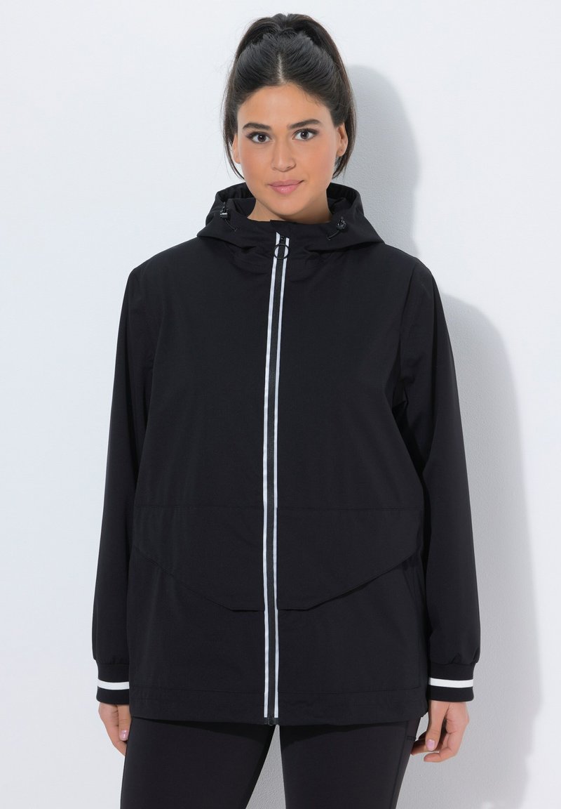 Czarna kurtka z kapturem i suwakiem z przodu, z białymi paskami jako akcentami oraz luźnym krojem. Materiał wydaje się lekki, odpowiedni do noszenia warstwowego.