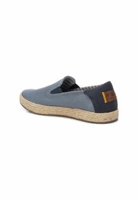 Zapato slip-on de lona azul con paneles elásticos en los lados, suela de yute y detalles en marino en el talón. Presenta un forro de tela con patrón.