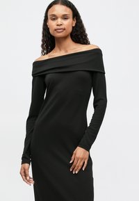 Μαύρο φόρεμα με άνοιγμα στους ώμους, μακριά μανίκια, στενή σιλουέτα, απαλό υφασμάτινο τελείωμα, με μήκος μέχρι το γόνατο και ελαφρώς ριχτό ντεκολτέ.