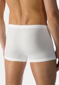 Boxer da uomo in cotone bianco con una morbida cintura elasticizzata, caratterizzati da una texture liscia e una vestibilità a vita media, che mostrano un design aderente.