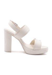 Valkoiset korkeat sandaalit paksuilla alustoilla, joissa on kaksi leveää hihnaa jalkapöydän yli, paksu neliön muotoinen korko ja sileä synteettinen materiaali.