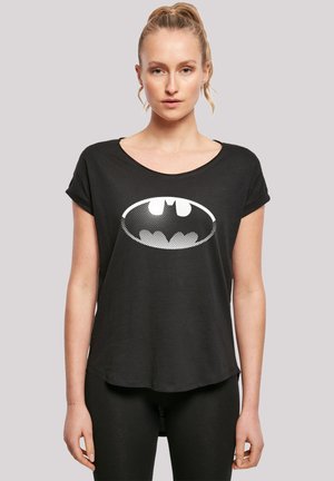 Svart t-skjorte med kort erme og vid hals, med et hvitt Batman-logo i halftone-mønster på forsiden, laget av myk stoff.
