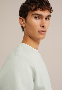 Mint green sweatshirt with a round neckline and visible seam details, made of soft fabric. Features a relaxed fit and minimalistic design.