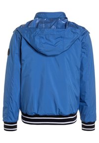 Giacca in nylon blu con cappuccio, caratterizzata da un orlo e polsini a coste bianchi e neri. Texture liscia, design casual e dettagli minimi.