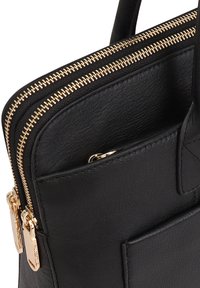 Zwarte leren tas met dubbele goudkleurige ritsen, een textuur oppervlak en een klein voorvak met een gestikte detail.