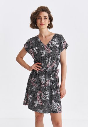 Czarna sukienka krótki rękaw z białymi kropkami i kwiatowo-paisley'owym wzorem w odcieniach różu i bieli. Dekolt w kształcie litery V z paskiem w talii.