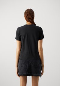 Black cotton t-shirt with short sleeves, crew neck, and a soft texture, paired with a black denim skirt featuring pockets and frayed hem.