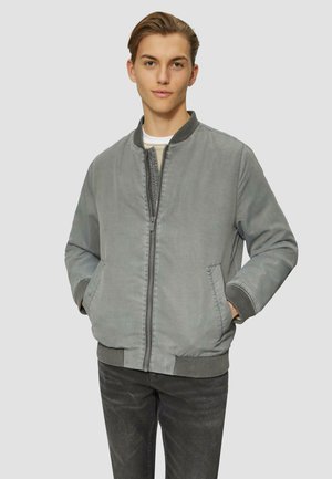 Gray bomber jacket with ribbed collar and cuffs, zip closure, side pockets, and a soft texture, paired with dark jeans.