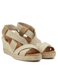 Wedge sandals with soft, beige canvas and brown suede straps. Features a jute-wrapped platform and cross-strap design for support.