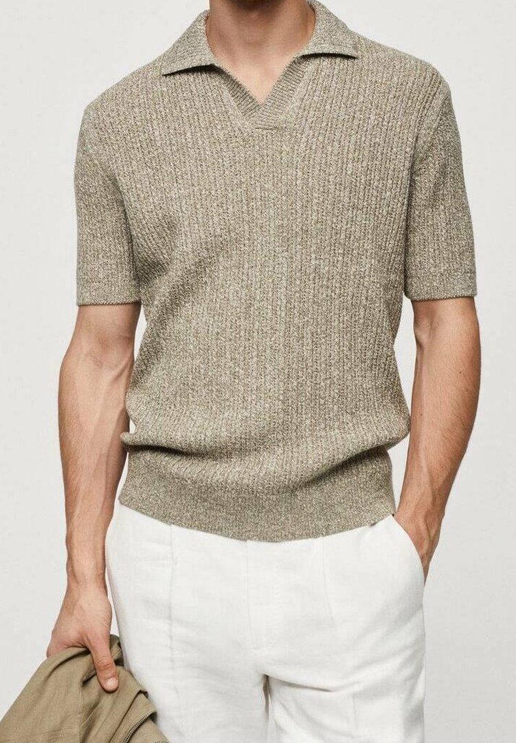 Homme portant un polo en maille beige à manches courtes et un pantalon blanc, tenant une veste beige dans sa main gauche.