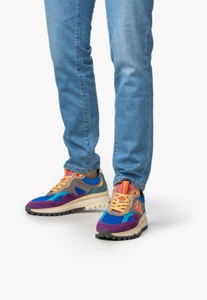 Colorful sneakers featuring blue, purple, and tan textile upper, with orange laces, patterned accents, and a rugged rubber sole.