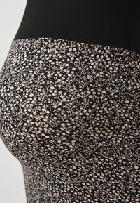 Μαύρες κολάν με λουλουδάτο σχέδιο που διαθέτουν υφή με μικρά λευκά λουλούδια σε μαύρο φόντο. Ελαστικό υλικό.