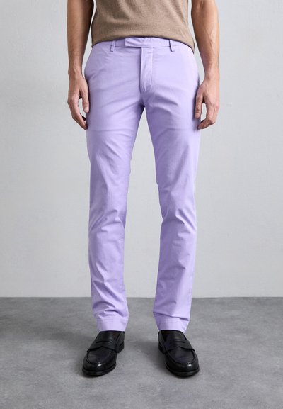 Vaaleanvioletit puuvillahousut, joissa on slim fit ja hienovarainen rakenne. Tasainen etuosa ja vyölenkit, yhdistetty mustiin loafereihin.