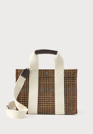 Bolsa retangular de tecido xadrez marrom com largas alças verticais brancas, pega curta de couro e alça de ombro ajustável branca, em fundo branco.