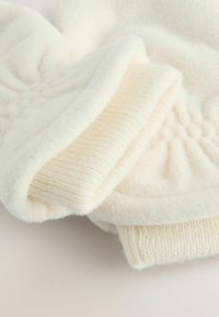 Soft cream-colored fleece fabric with knit ribbed cuffs, folded on a light surface.