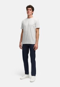 Grå bomull t-skjorte med rund hals, kombinert med marineblå bukser og hvite sneakers, med et rent og minimalistisk design.