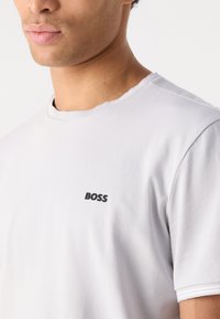 Fehér pamut póló fekete "BOSS" logóval a bal mellen, kerek nyakkivágással és rövid ujjakkal. Puha tapintás és letisztult dizájn.