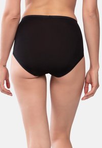 Slip nero a vita alta realizzato in tessuto liscio, con un design senza cuciture e cuciture sottili, delineato in vita e sulle gambe.
