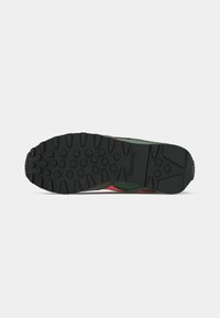 Crni gumeni potplat s istaknutim uzorkom, s naglašenim zelenim i crvenim motivima. Čvrsta tekstura s utisnutim Reebok logotipom.