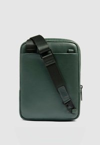 Borsa in pelle verde con texture liscia, forma rettangolare, tracolla regolabile in nylon nero e tasca laterale con cerniera.
