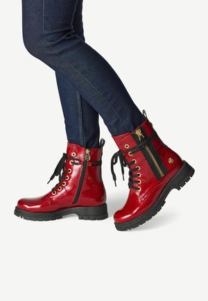 Botas de tobillo de charol rojo con acentos negros, parte delantera con cordones, lado con cremallera, suela de goma gruesa y detalles en dorado.