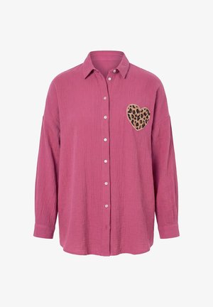 Camisa rosa de manga larga con botones, tela texturizada y un parche en forma de corazón con estampado de leopardo en el pecho izquierdo.