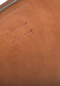 Brown leather wallet featuring a smooth texture, a silver zipper, and subtle stitching details. Background is solid and unobtrusive.