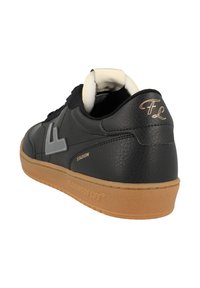 Black leather sneaker with gray logo, cushioned tongue, and gum rubber sole. Features subtle branding and textured patterns on the upper.
