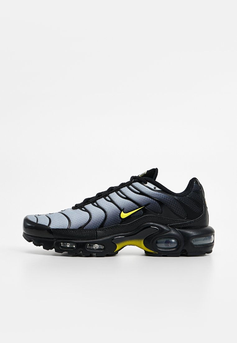 Chaussures Nike Air Max avec un upper lisse gris et noir aux motifs en vagues, accents jaunes et une semelle noire épaisse avec un coussin d'air visible.